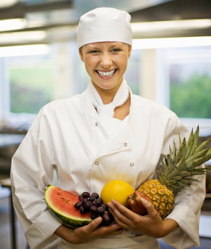 Retrato de una chef femenina sosteniendo frutas frescas, destacando su profesionalismo y pasión por la cocina