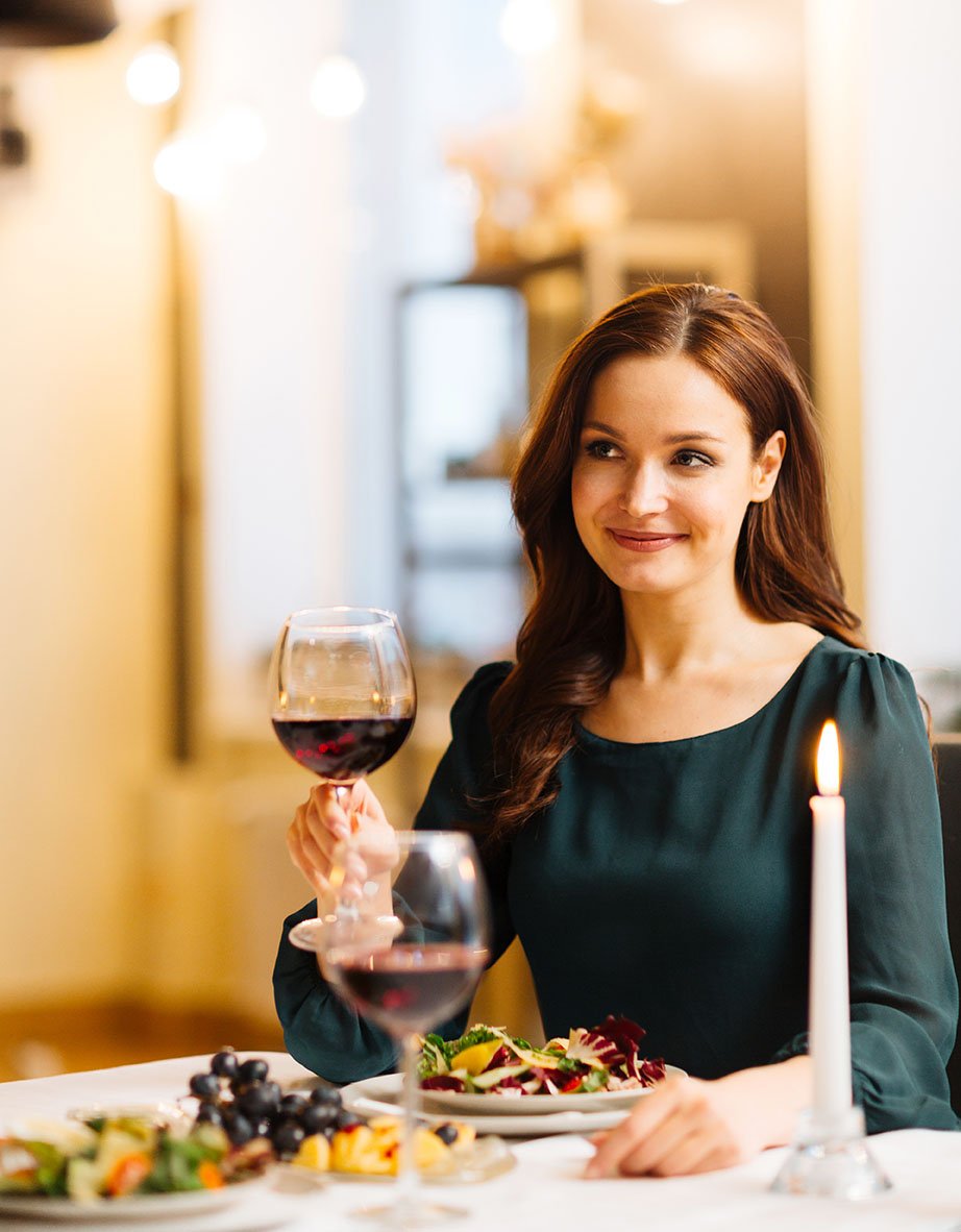 Comensal femenino sosteniendo una copa de vino para un brindis.